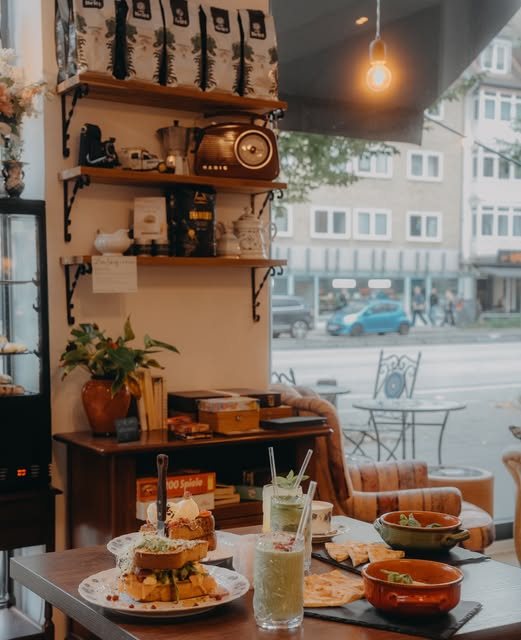 Blick durch das Café auf die Grindelallee, vorn ein Tisch mit Sandwich und Limonade