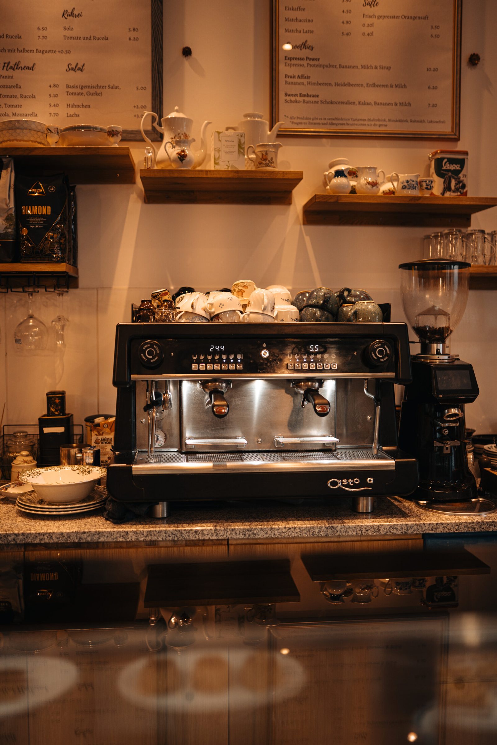 Die Siebträgermaschine an der Bar des Café Love Story mit Regalen voller Tassen