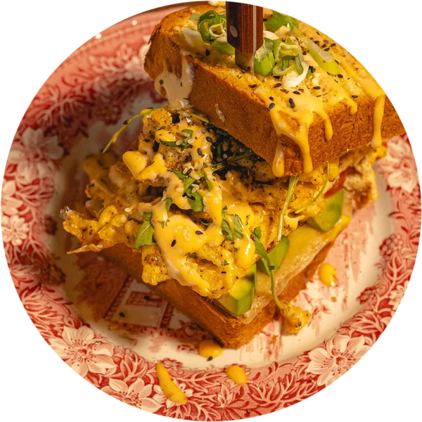 Egg Drop Sandwich The Scrambled Gentleman mit Rührei, Käse und Avocado auf einem roten Vintage-Teller