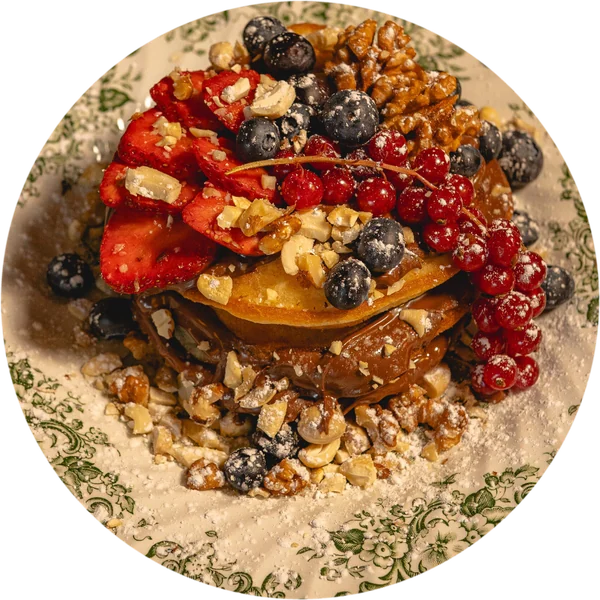French Toast Sweet Temptation mit Erdbeeren, Blaubeeren, Johannisbeeren und Walnüssen auf einem grünen Vintage-Teller